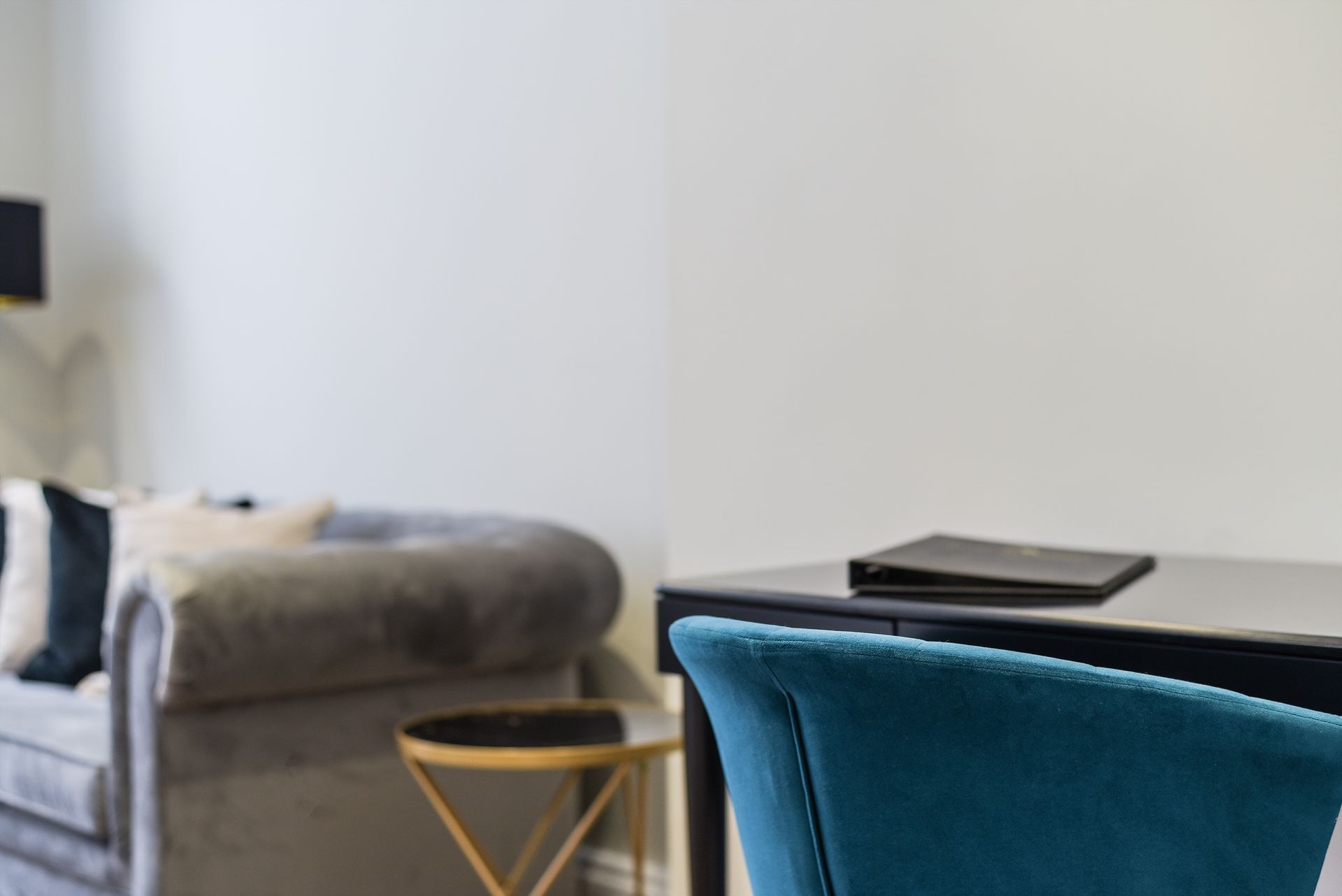 Modern living room with a gray sofa, round side table, and teal chair in the foreground.