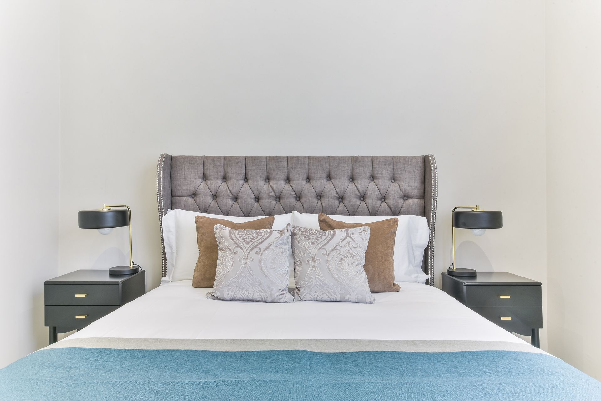 Modern bedroom with a tufted gray headboard, white bedding, and matching bedside lamps