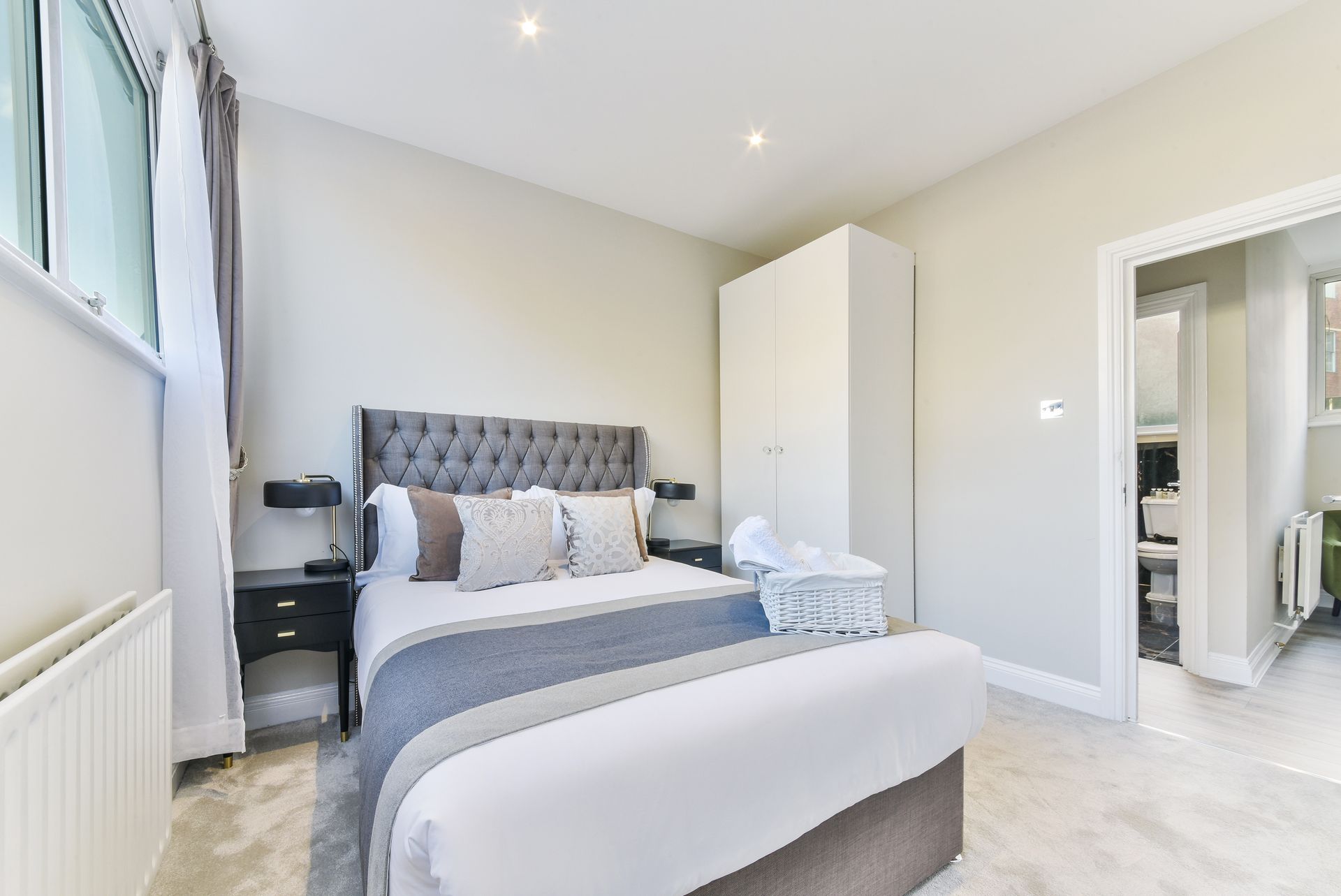 Bright modern bedroom with gray bed, white wardrobe, and open doorway