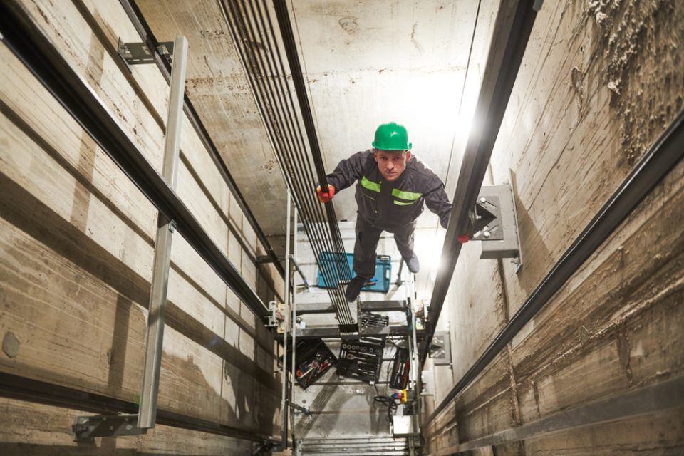 Tecnico nel vano ascensori per un servizio di manutenzione