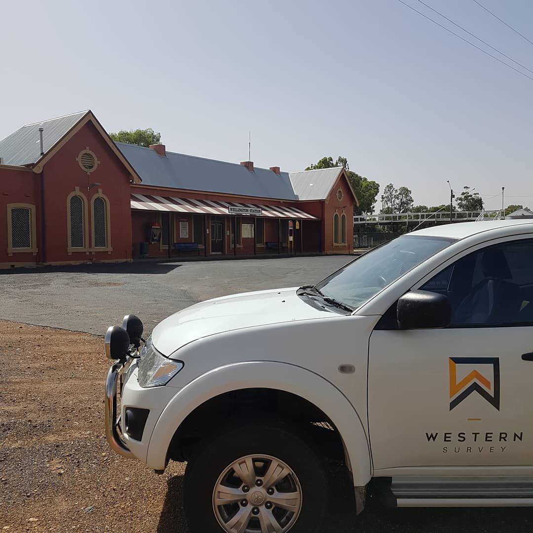 A White Western Hotel Truck Is Parked In Front Of A Red Building — Western Survey Pty Ltd In Dubbo, NSW