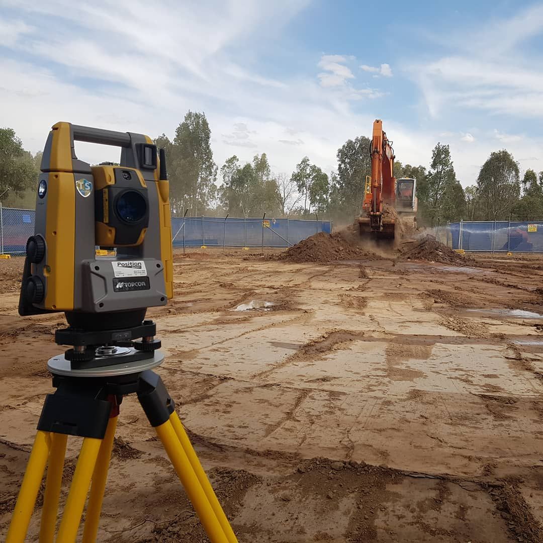 A Yellow Theodolite Is On A Tripod In A Dirt Field — Western Survey Pty Ltd In Dubbo, NSW