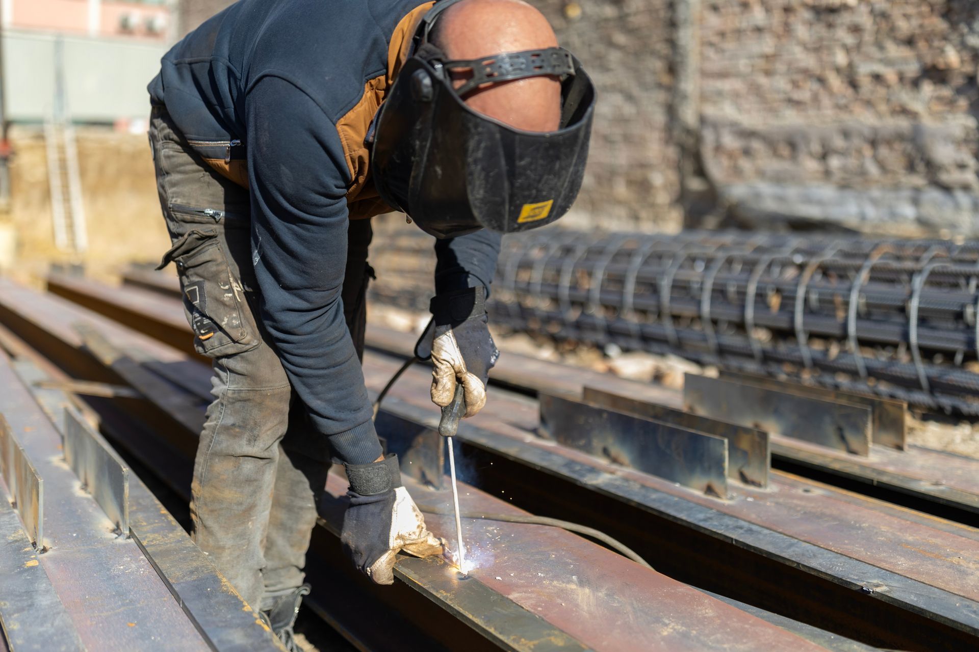 Foundation steel beam welding at a construction site with protective gear.