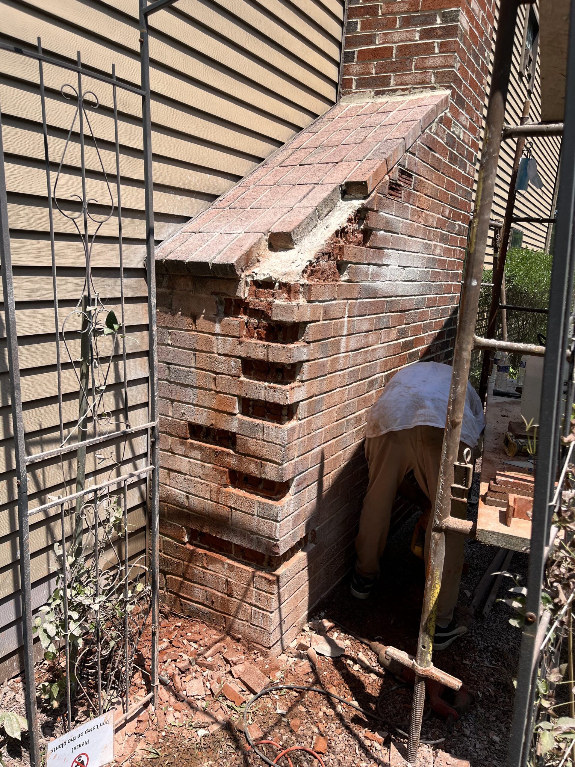 Brick outdoor barbecue grill with a chimney and a person working beside it in a narrow courtyard