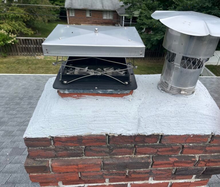 Rooftop chimney with metal vents and flue caps on a white-painted brick chimney stack