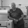 A man is leaning against a machine in a black and white photo.