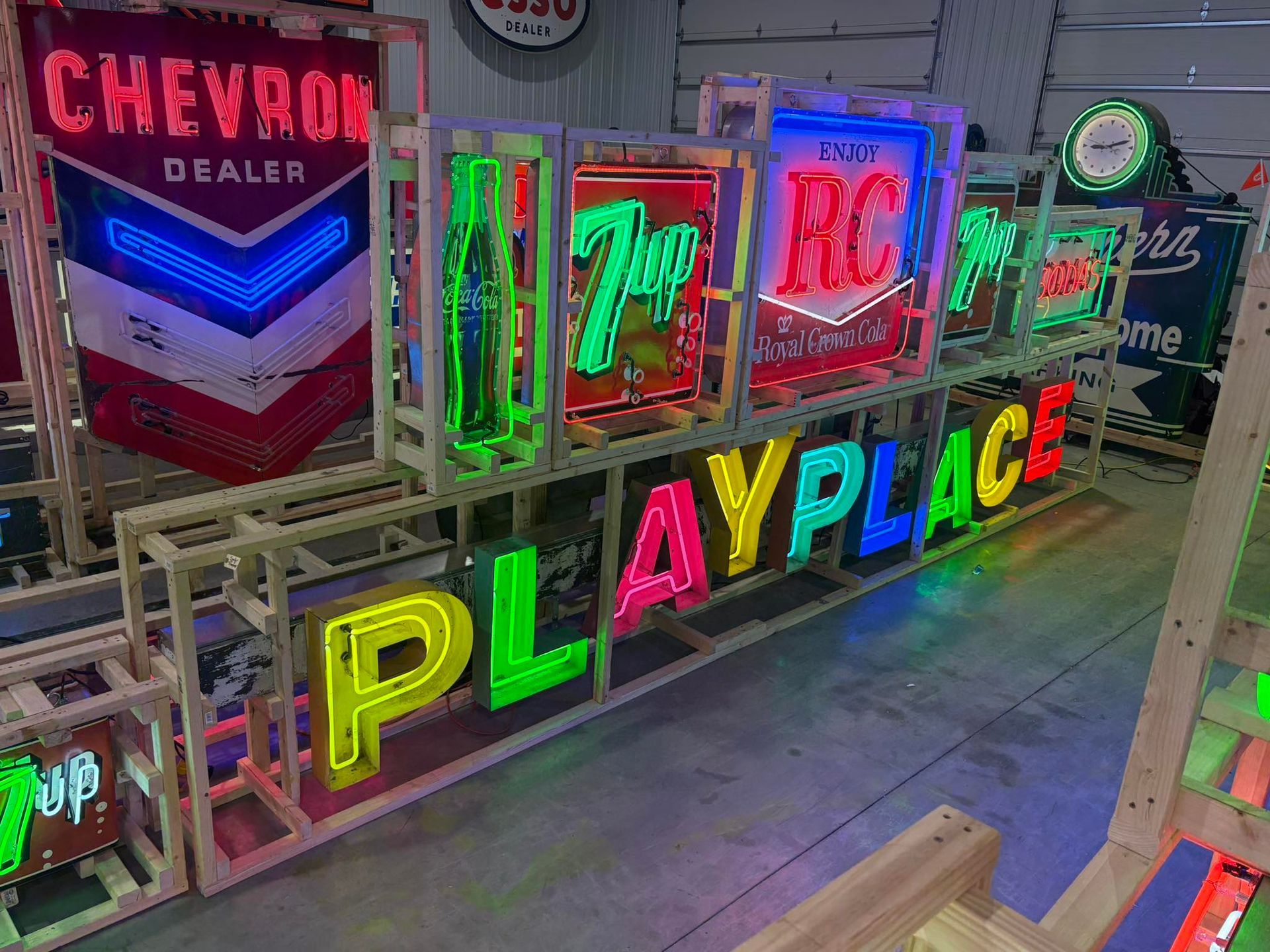 Neon sign display with colorful letters reading “PLAYLAND” and other bright signs in a lit walkway.