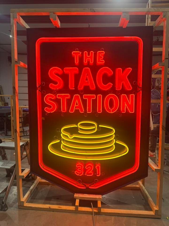 Neon sign reading “The Stack Station” in red and yellow inside a metal frame