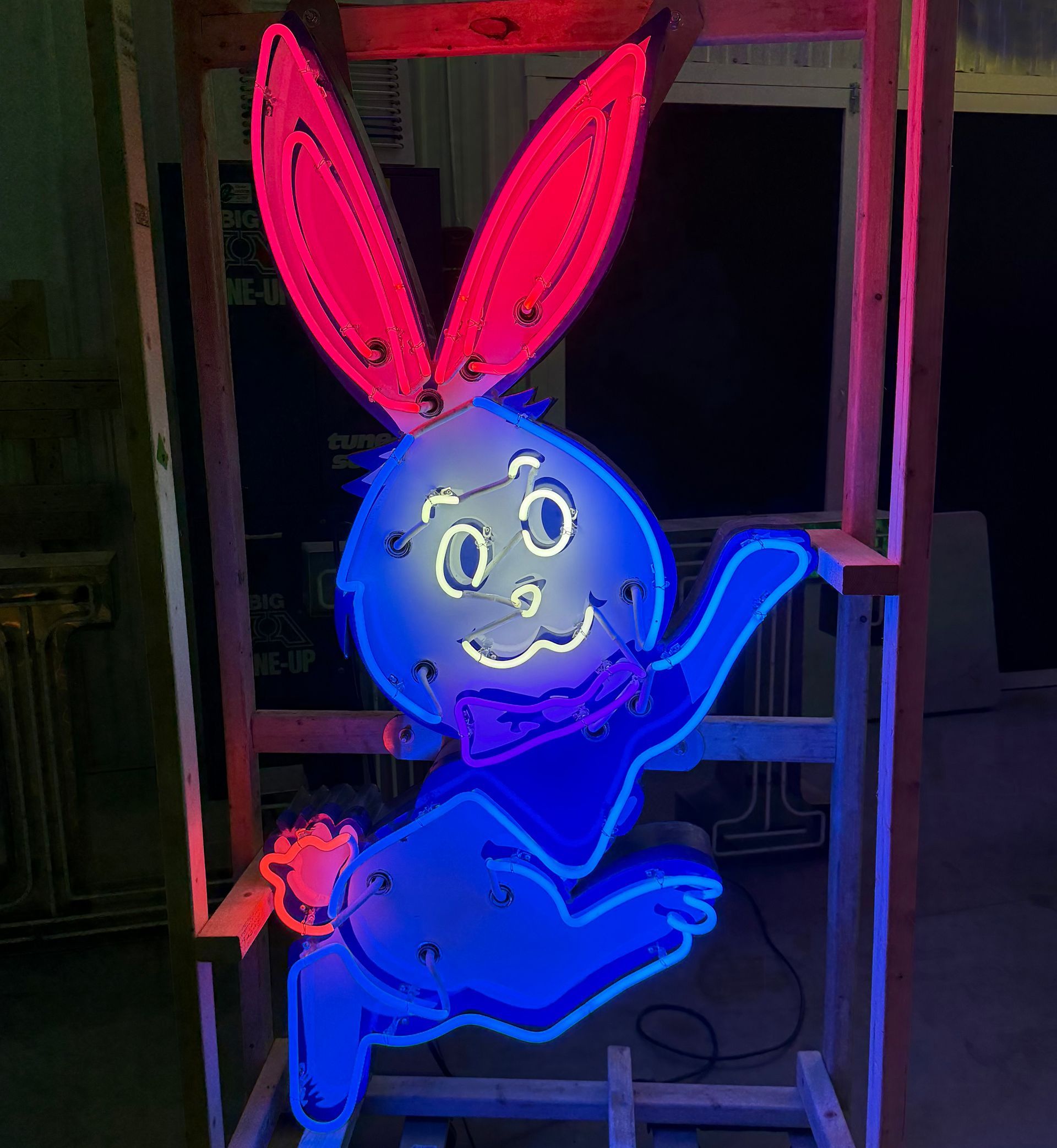 Neon blue rabbit with pink ears, waving with a smiling face.