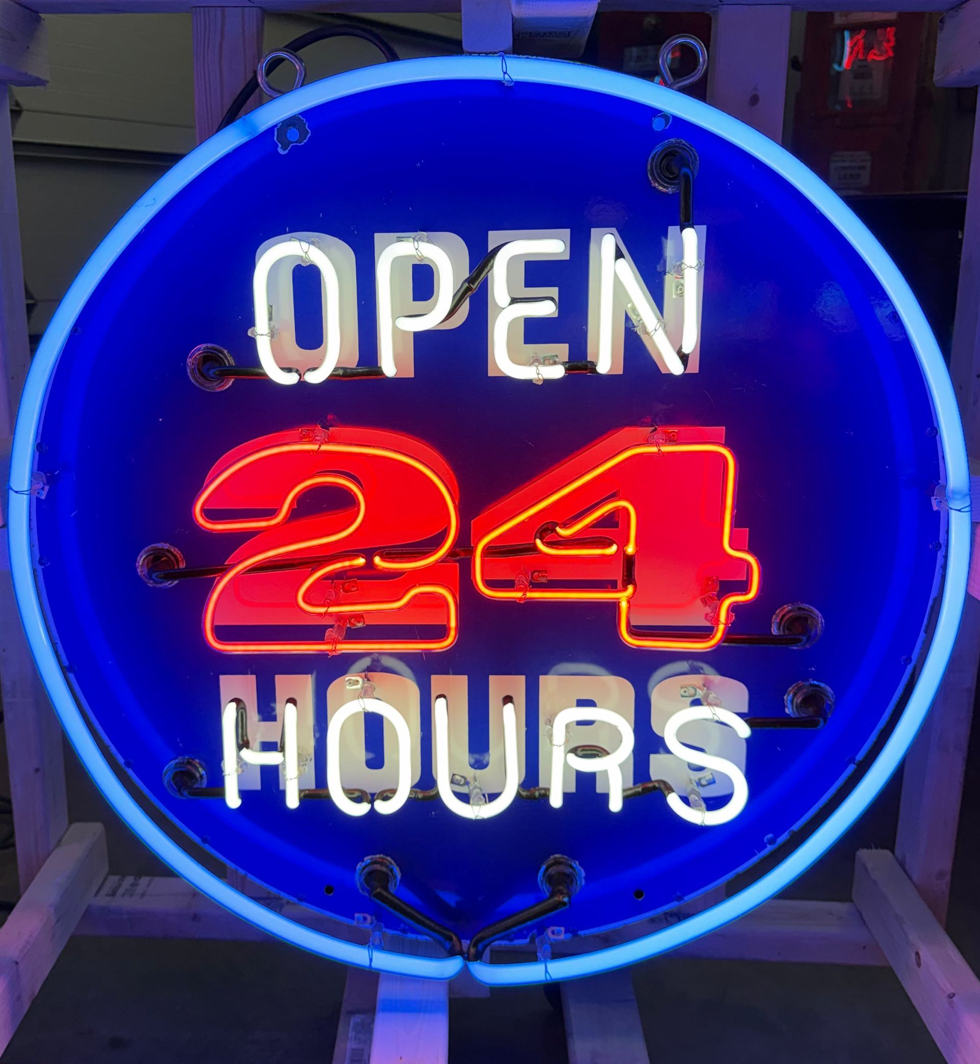 Blue neon “OPEN 24 HOURS” sign glowing at night