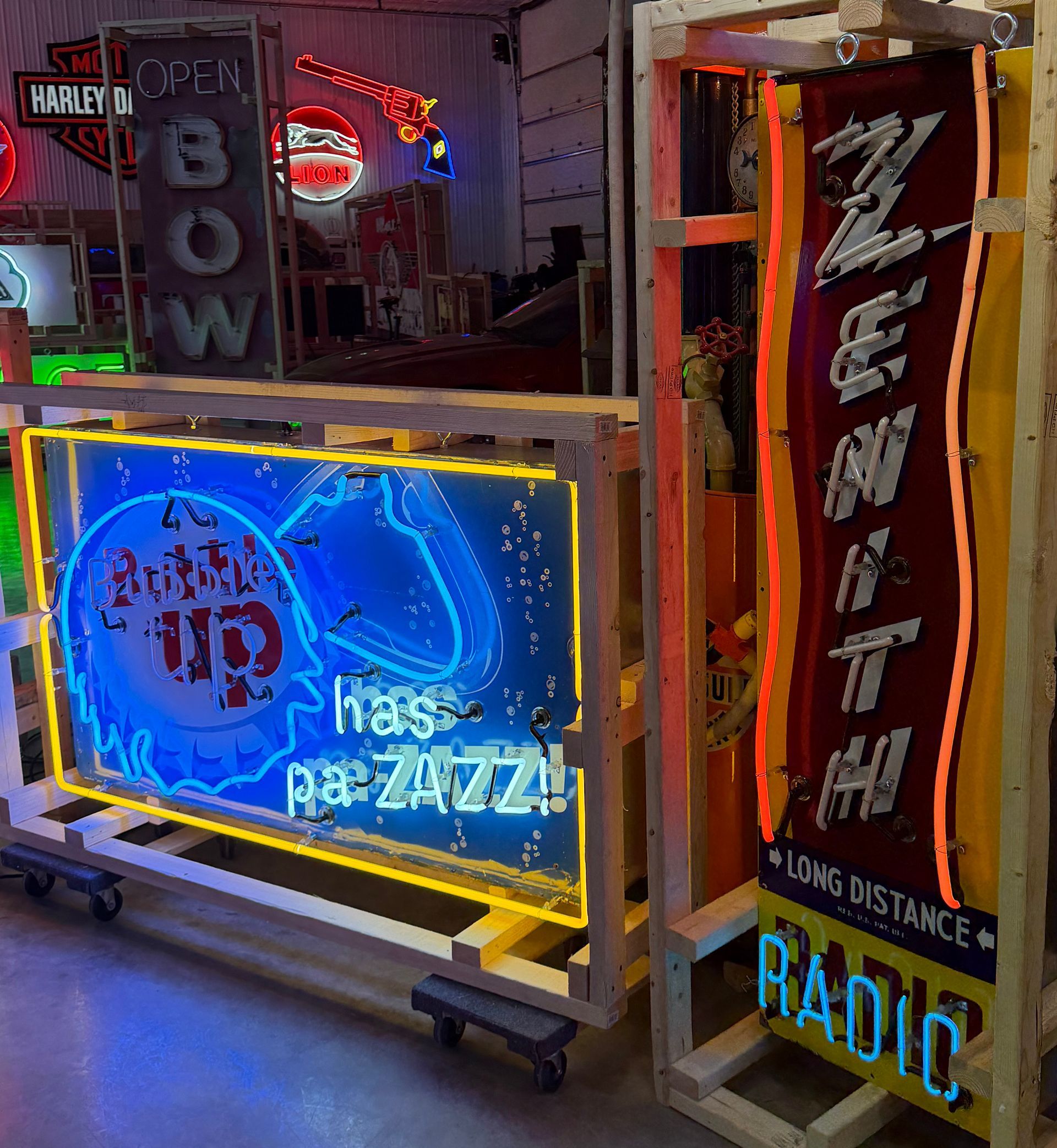 Colorful neon signs in a dim workshop, including a blue “buzz” sign and a tall “ZENITH RADIO” sign.