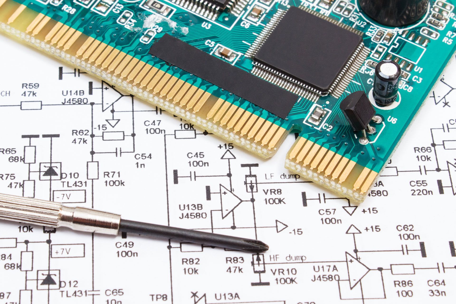 Circuit board and screwdriver on top of a schematic diagram.