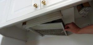 A person is cleaning a hood in a kitchen.
