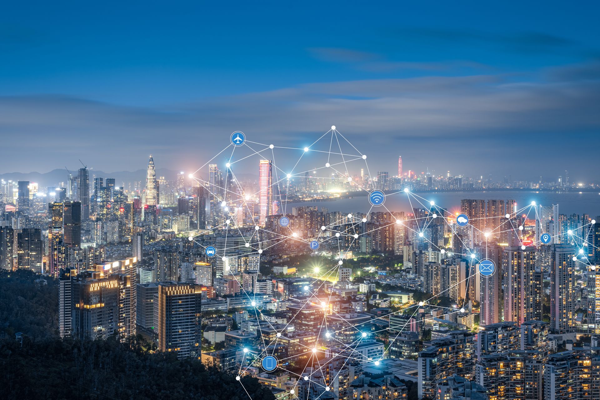 City skyline at night with digital network connections overlaid; blue and white lights.
