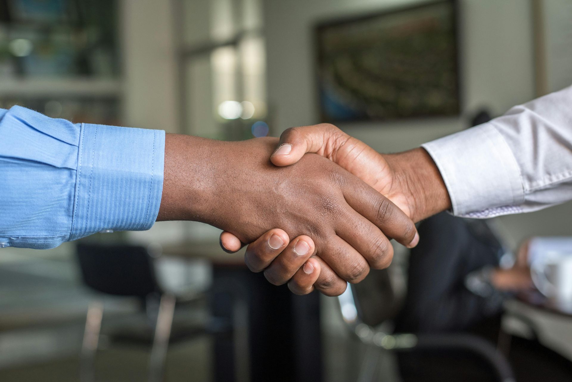 Two hands shaking, a light-skinned hand gripping a dark-skinned hand in a business setting.
