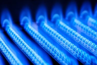 Un gros plan d'un brûleur à gaz avec des flammes bleues qui en sortent.