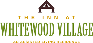 Logo for The Inn at Whitewood Village, an assisted living residence, featuring a dark roof icon over green text.