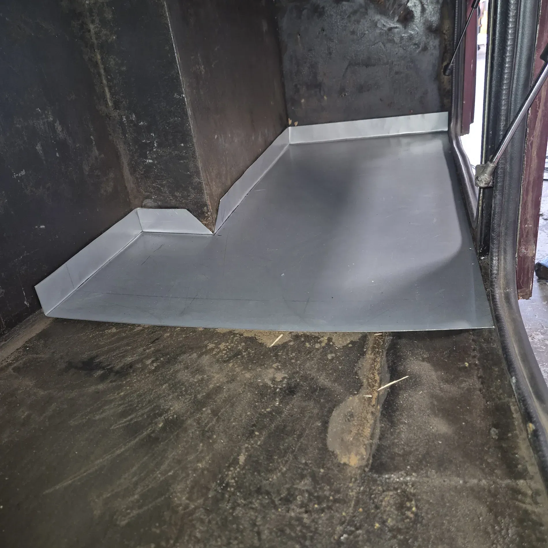 Inside a dark space, a silver metal panel covers a section of a dirty floor — Revive Caravan Repairs in Kippa-Ring, QLD