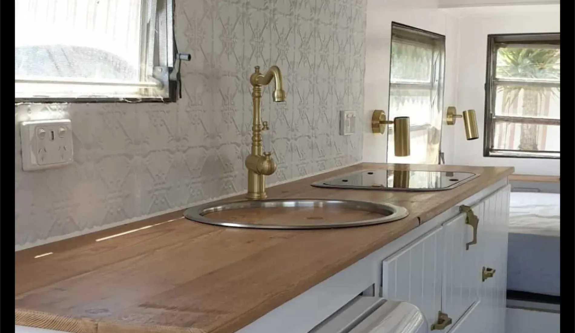 A modern kitchen counter with a brass faucet, sink, and stovetop, next to a window — Revive Caravan Repairs in Kippa-Ring, QLD