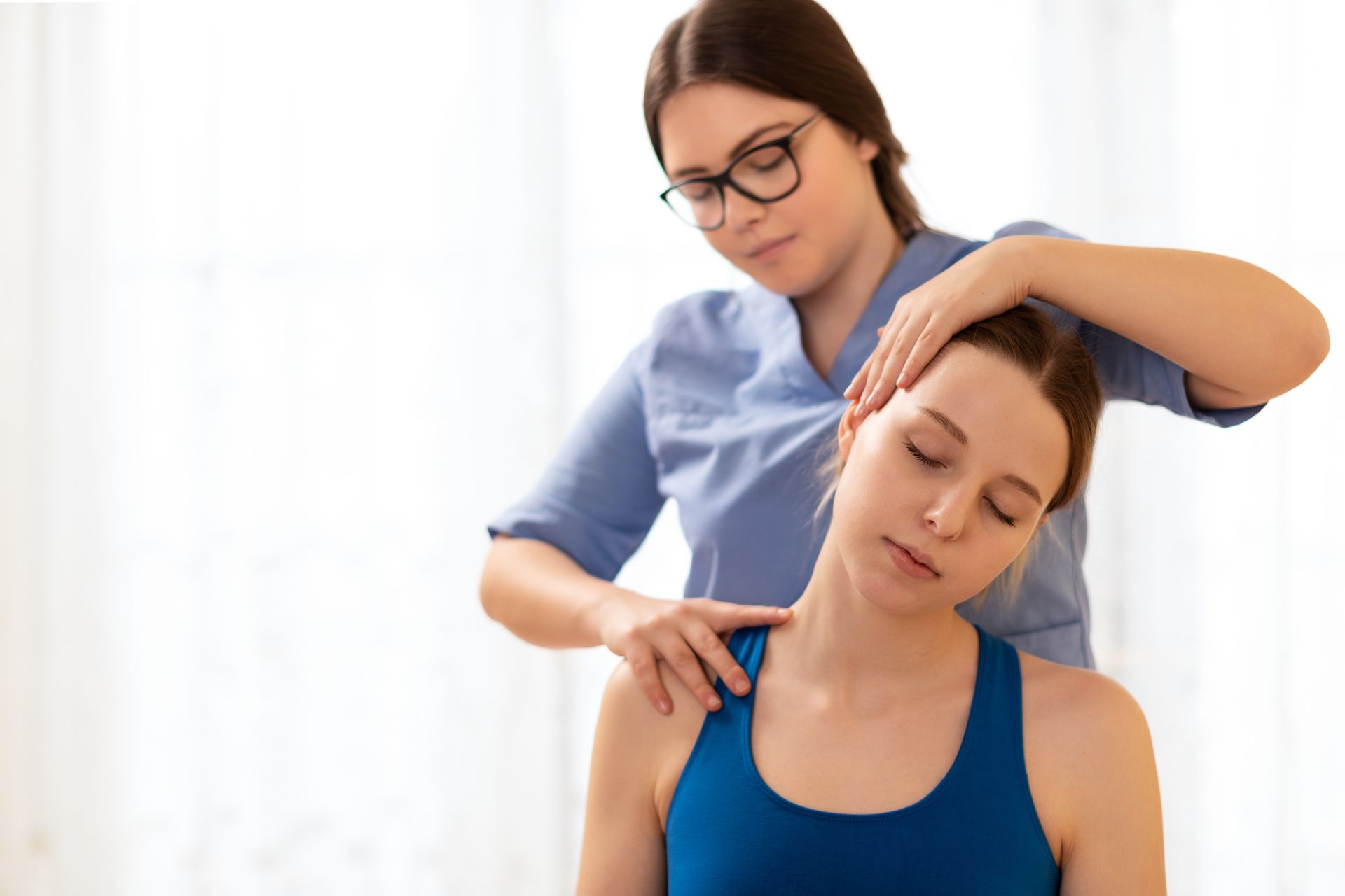 Physical therapist massaging a patient’s neck and shoulders in a bright clinic