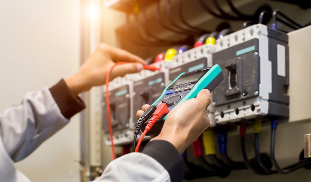 An Electrician Is Working On An Electrical Box With A Multimeter — Commercial Electrician In Wagga Wagga, NSW