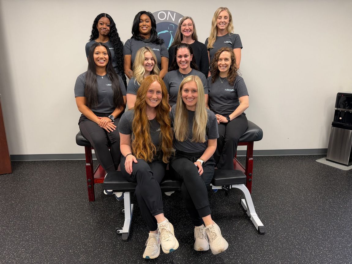 A group of women are posing for a picture while sitting on a table.