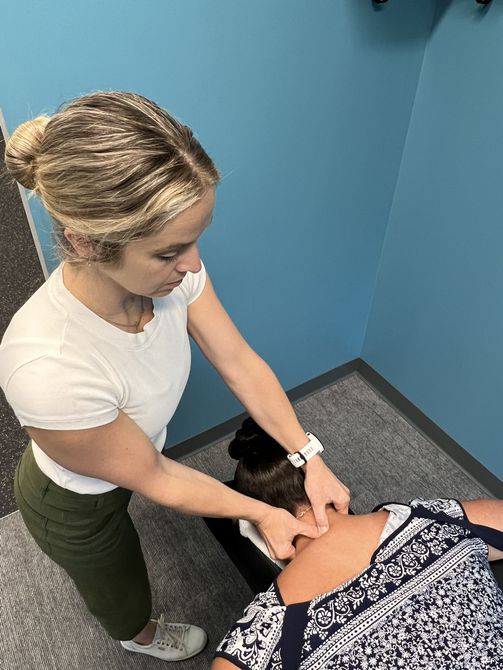 A woman is giving a massage to another woman in a blue room.