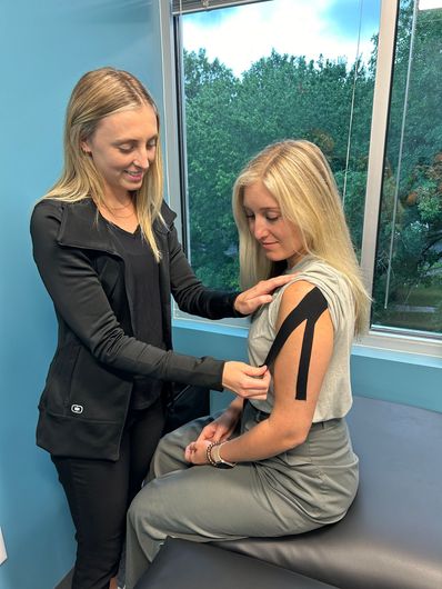A woman is putting tape on another woman 's arm