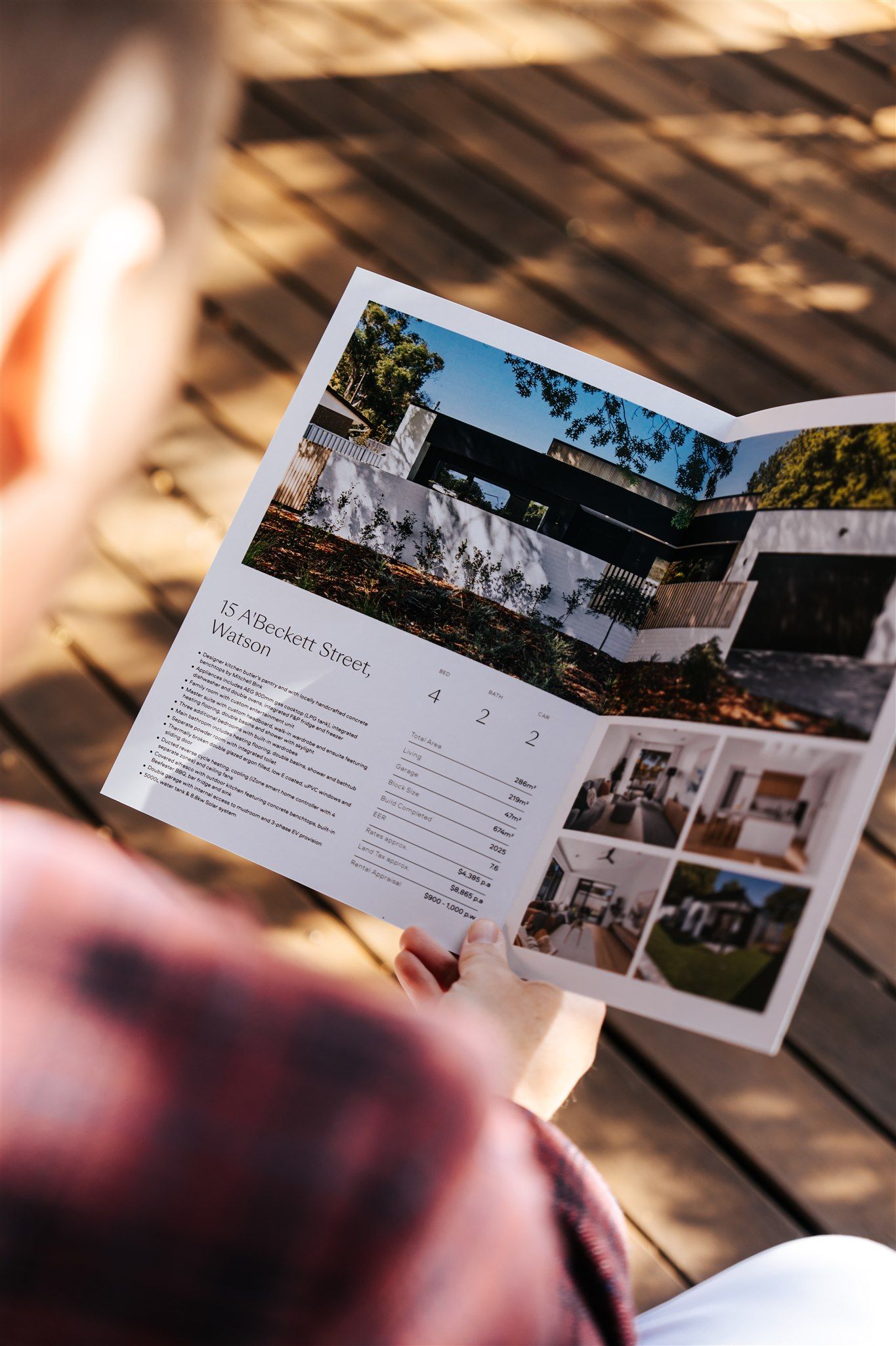 Pamphlet of houses over someone's shoulder — Hyde Burchell Buyers Agents In Canberra, ACT