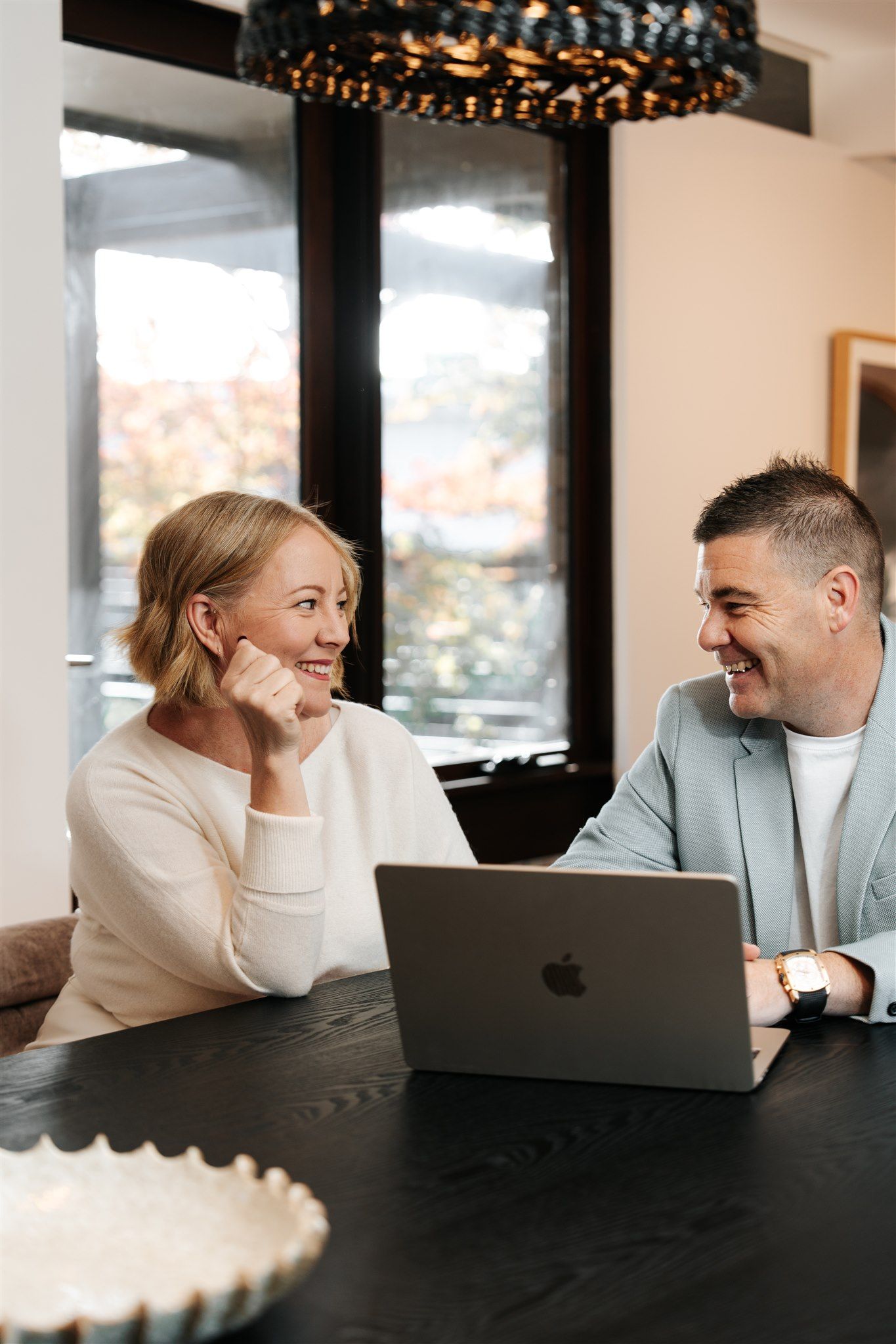 A Man and a Woman Are Talking at a table with a laptop — Hyde Burchell Buyers Agents In Canberra, ACT