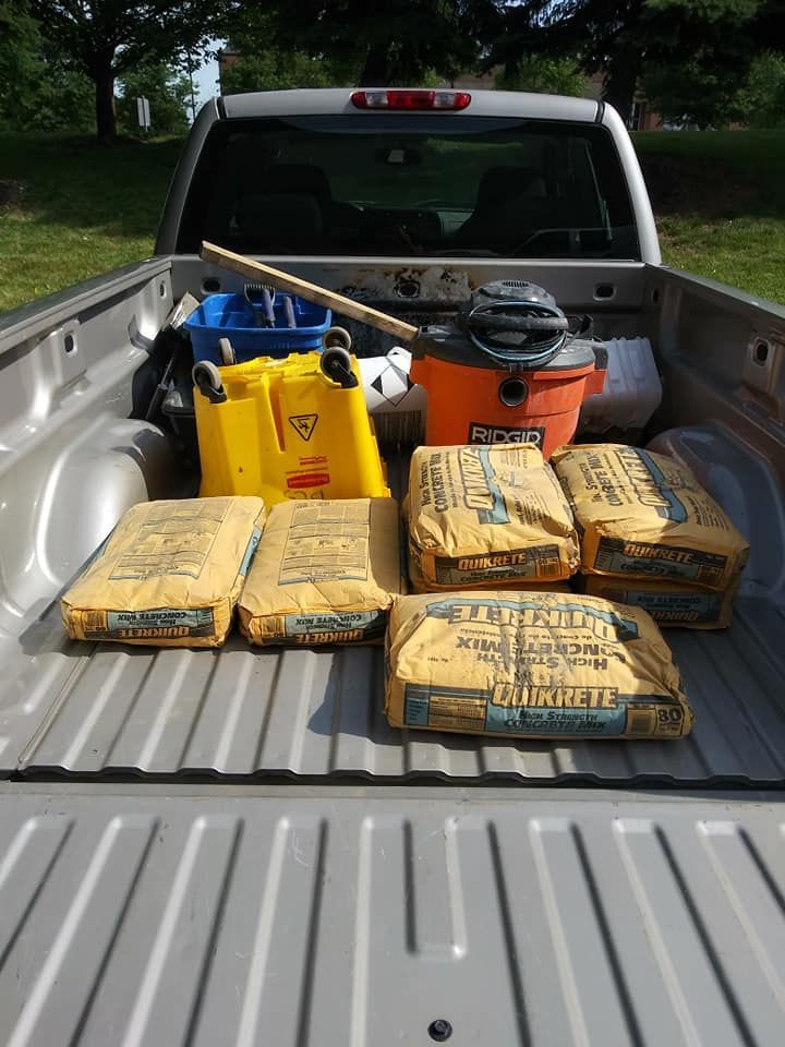 The back of a truck with bags of concrete and a vacuum cleaner