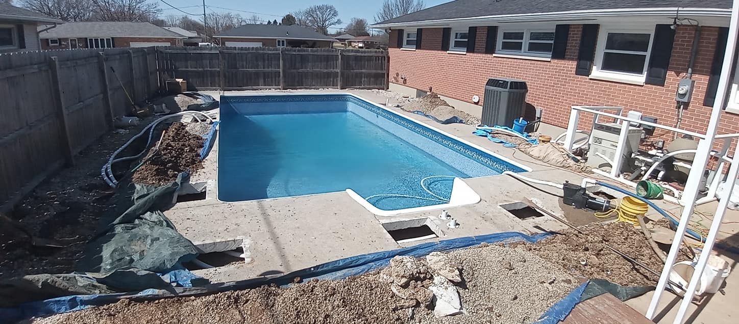 A swimming pool is being built in the backyard of a house