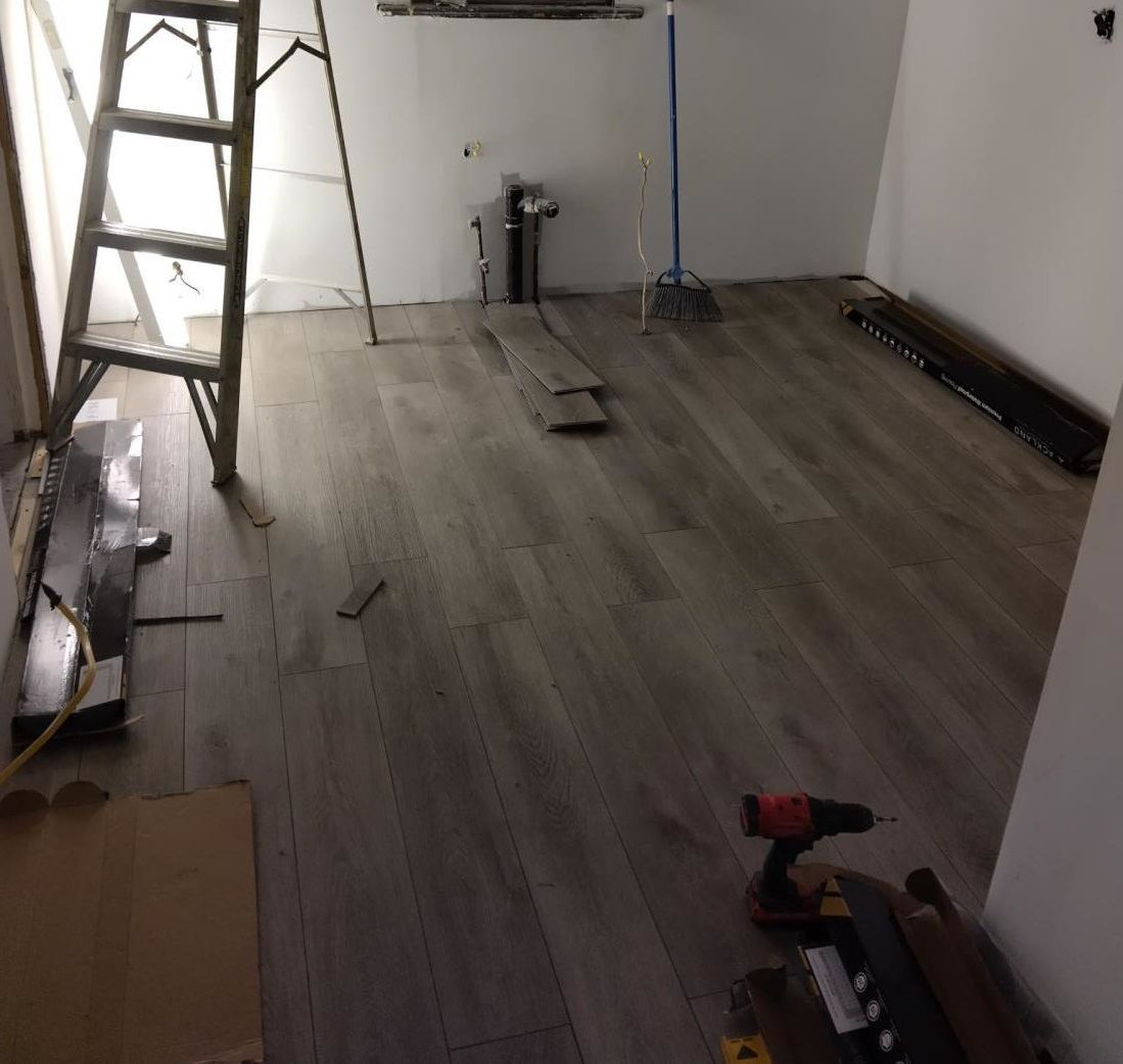 a man is working on a wooden floor with a hammer