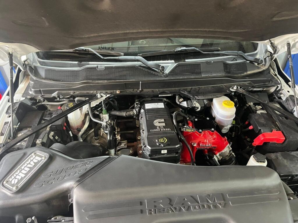 Open car hood showing engine bay with black and red components and a translucent fluid reservoir