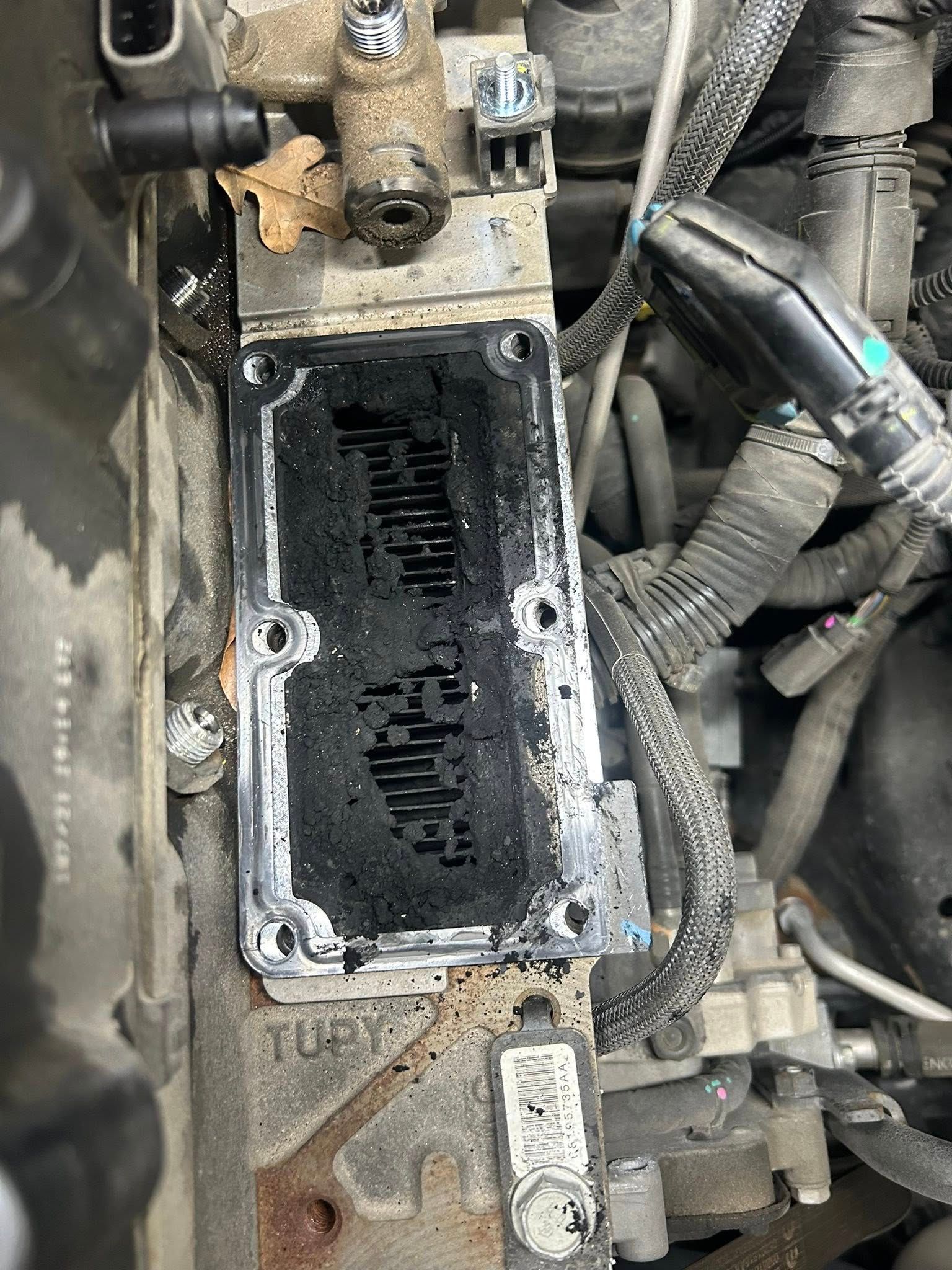 Close-up of an engine with a removed black intake manifold and exposed gasket opening.