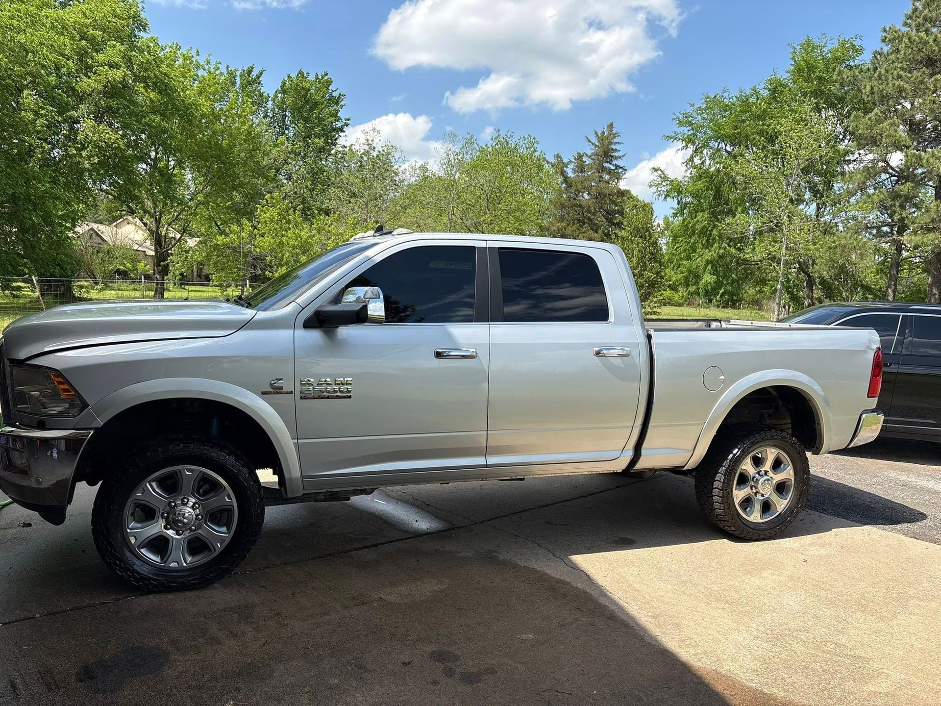 Silver pickup truck parked on a driveway under a partly cloudy sky