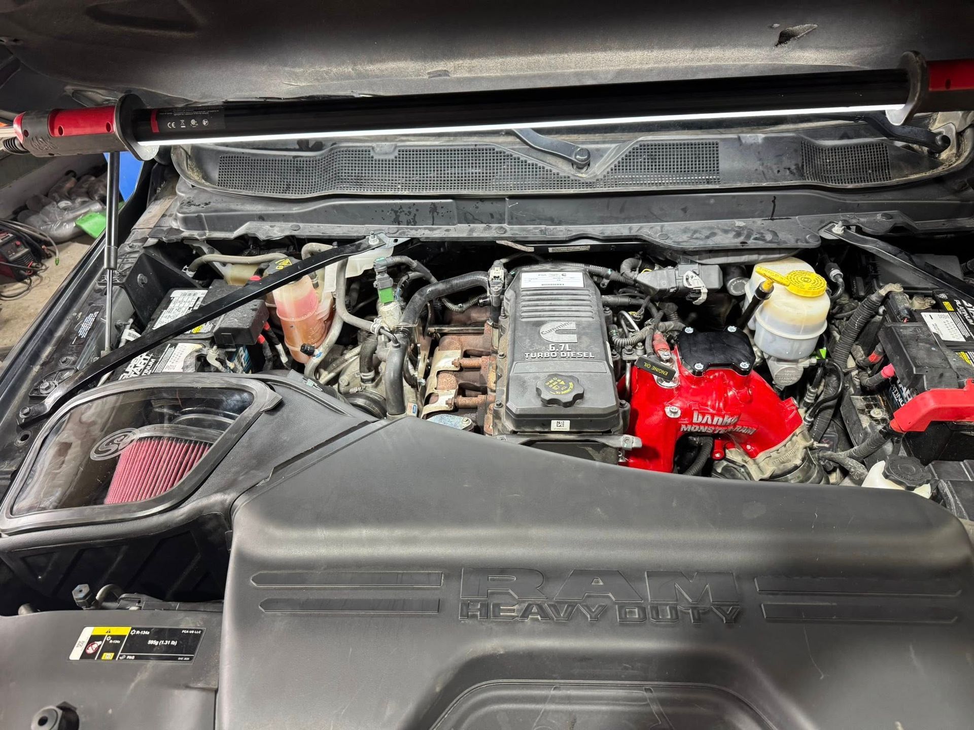Car engine bay with red components, black cover, and yellow fluid reservoir under the hood