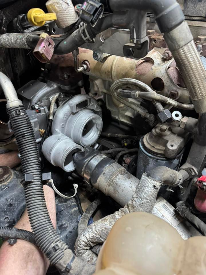 Engine bay with exposed turbocharger and hoses, showing dirty mechanical parts and components.