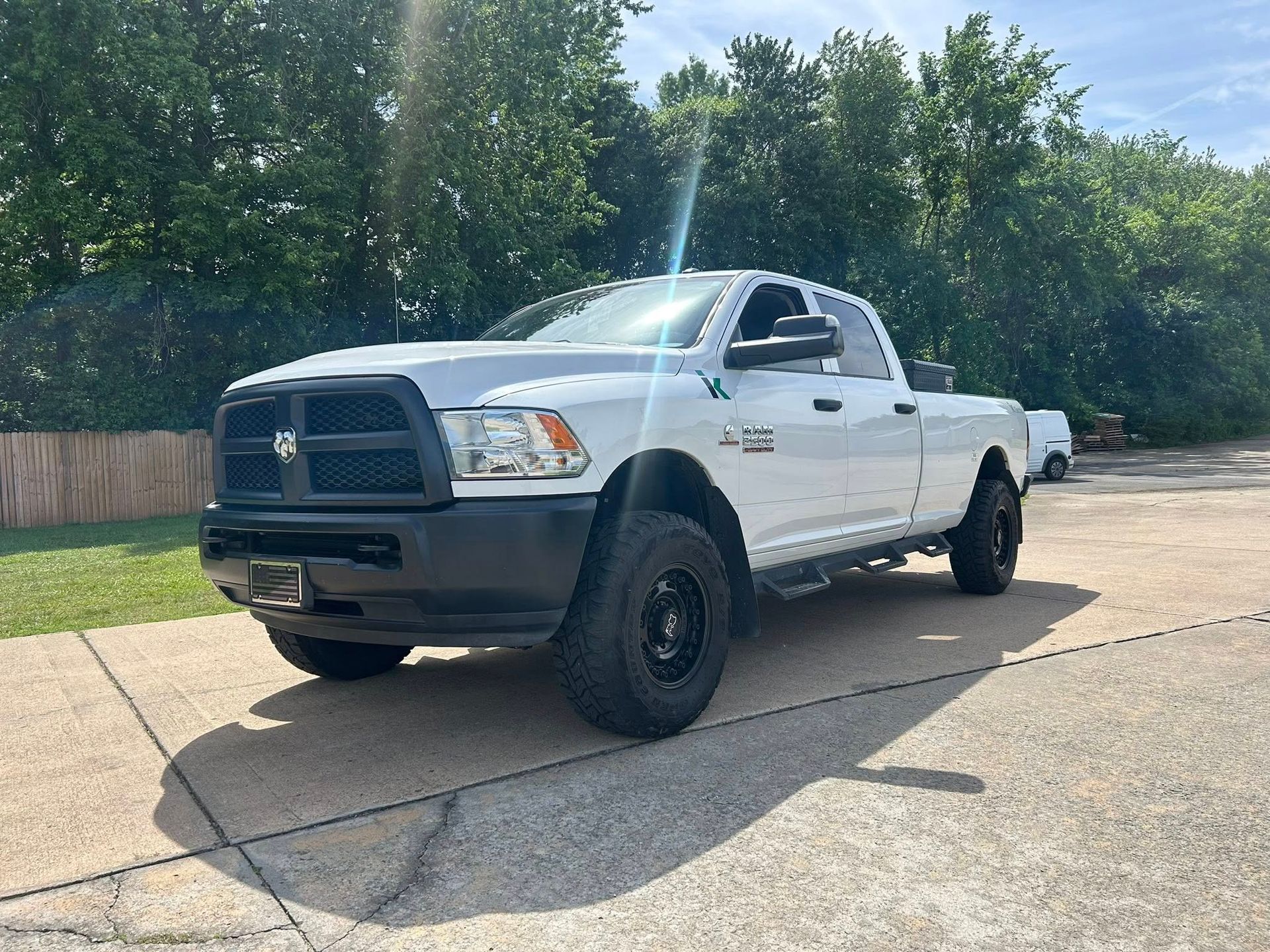 White pickup truck parked on a driveway beside trees, viewed from the front-left side.