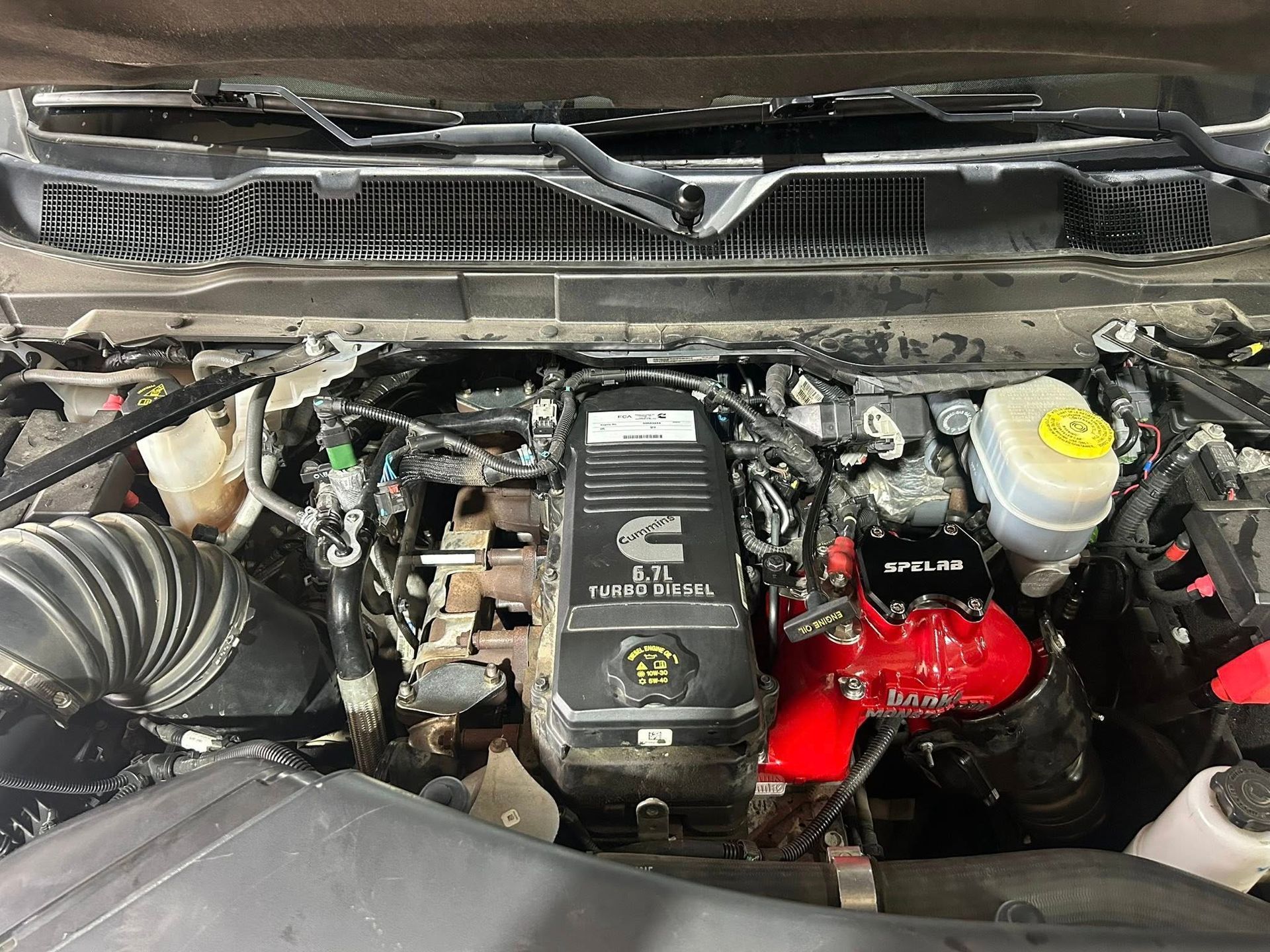 Car engine bay with red engine cover, black intake hose, and yellow fluid reservoir under the hood