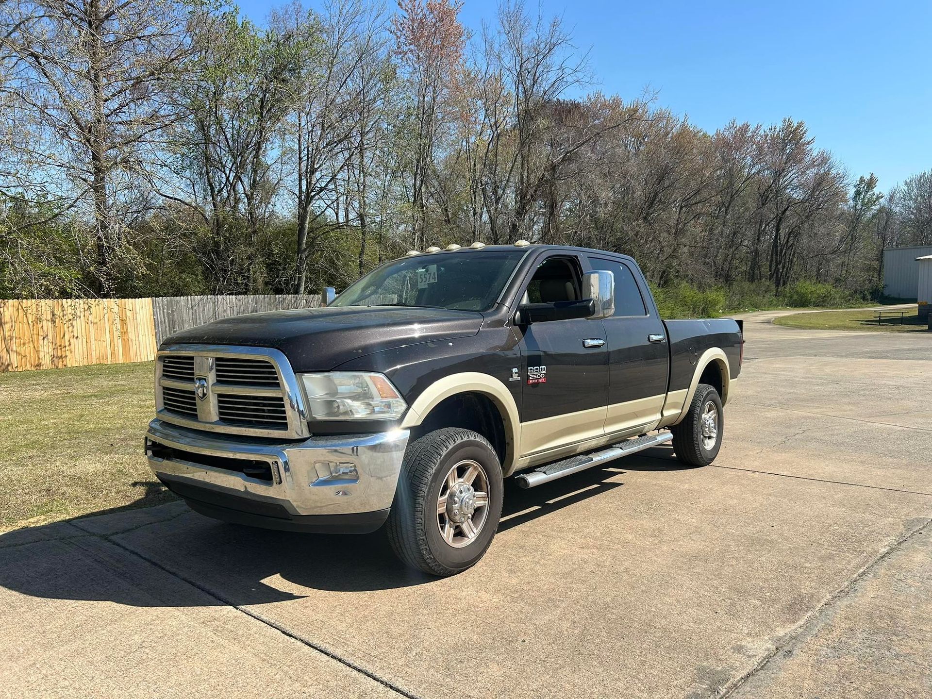 Black pickup truck parked on a gravel lot beside trees under a clear sky