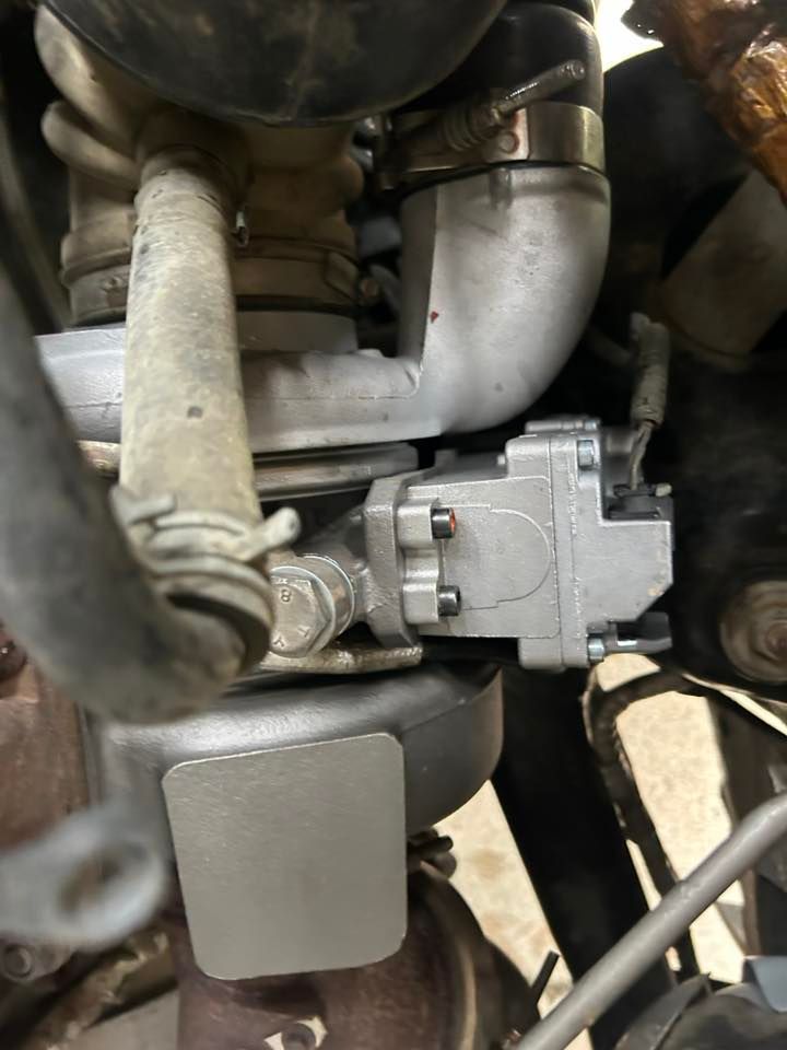 Close-up of a motorcycle engine and carburetor with hoses and metal components.