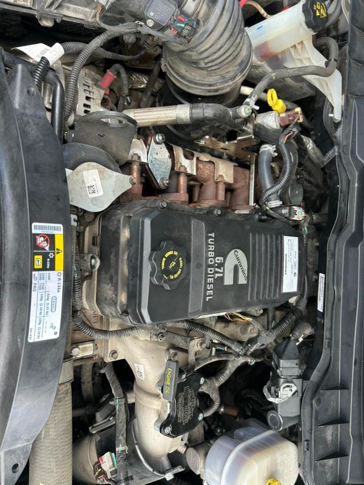 Engine bay with black air intake cover, hoses, and fluid reservoir inside a vehicle