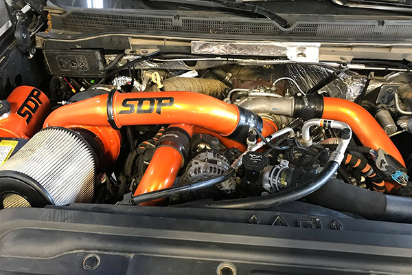 Modified car engine bay with bright orange SCT intake piping and air filter unit