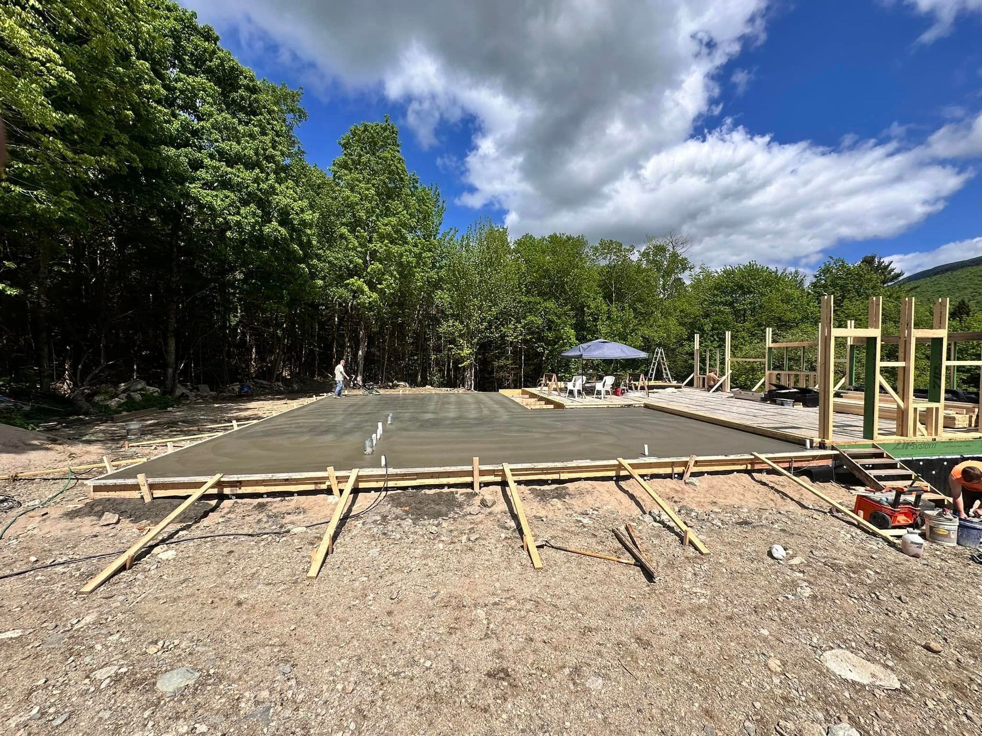A concrete foundation is being built in a yard with trees in the background.