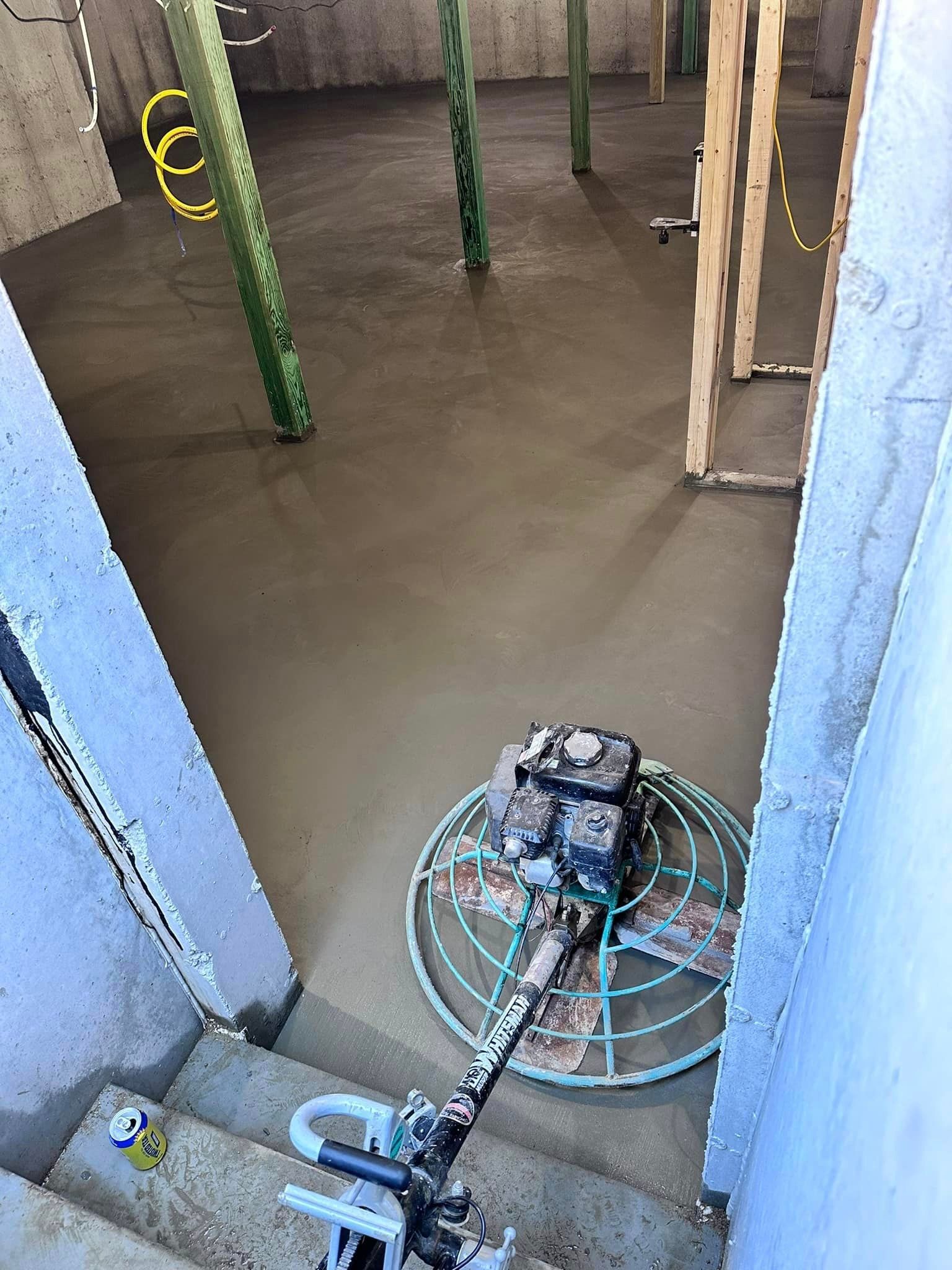 A machine is laying concrete on the floor of a building.