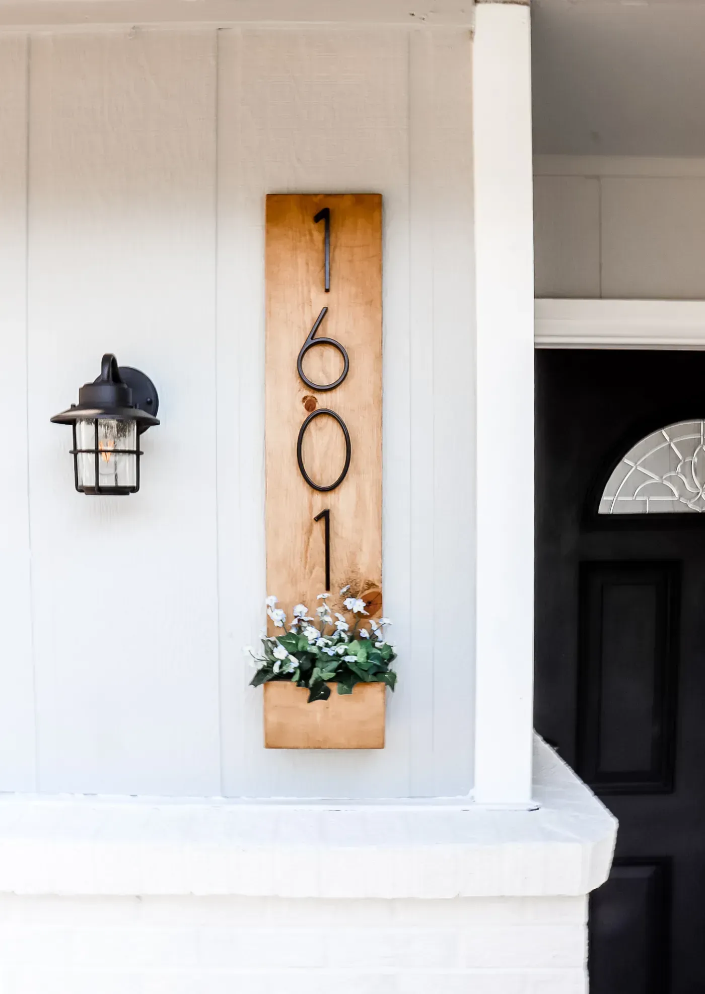 A wooden sign with the number 1601 on it is hanging on the side of a house.