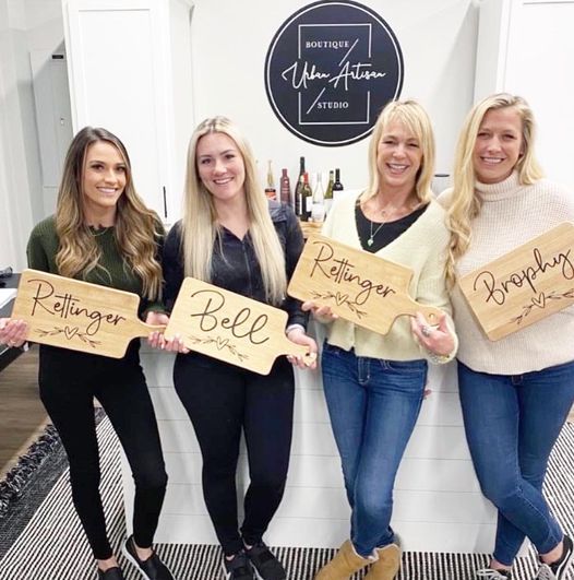A group of women are standing next to each other holding wooden signs.