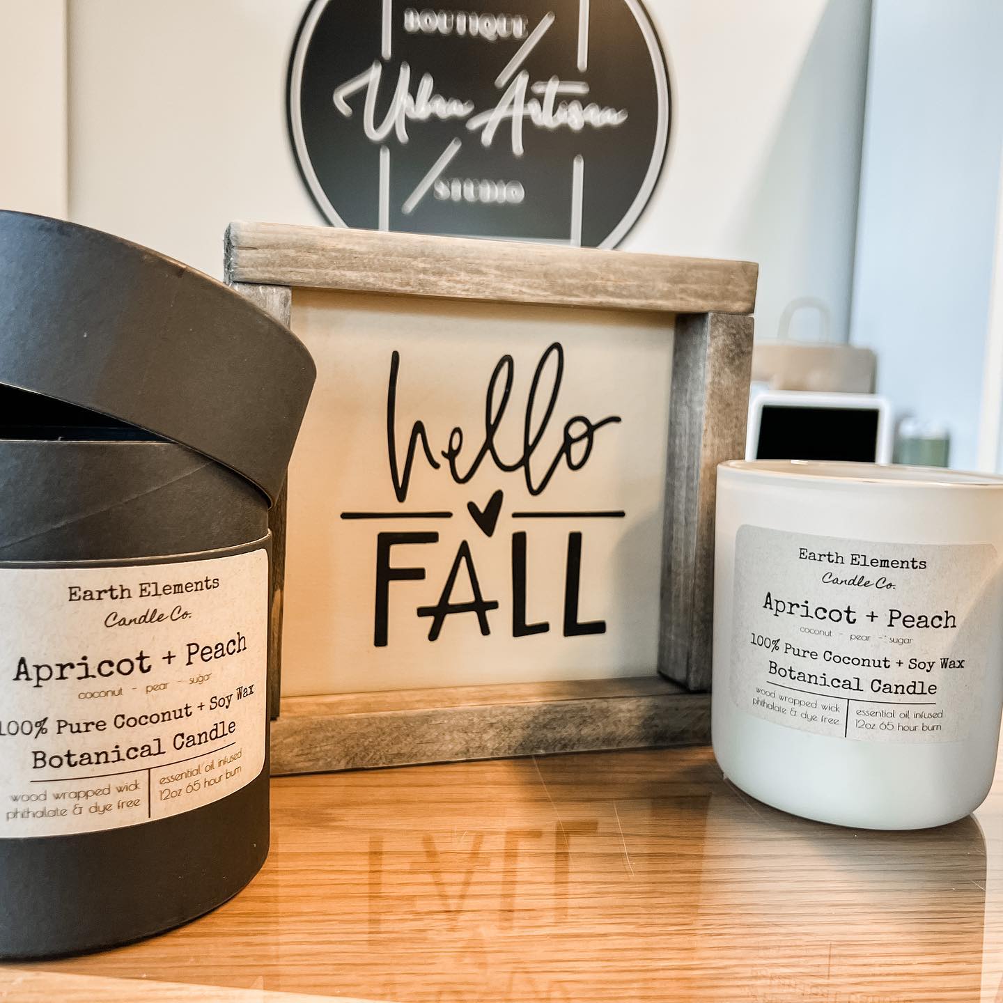 Two candles are on a table next to a sign that says hello fall