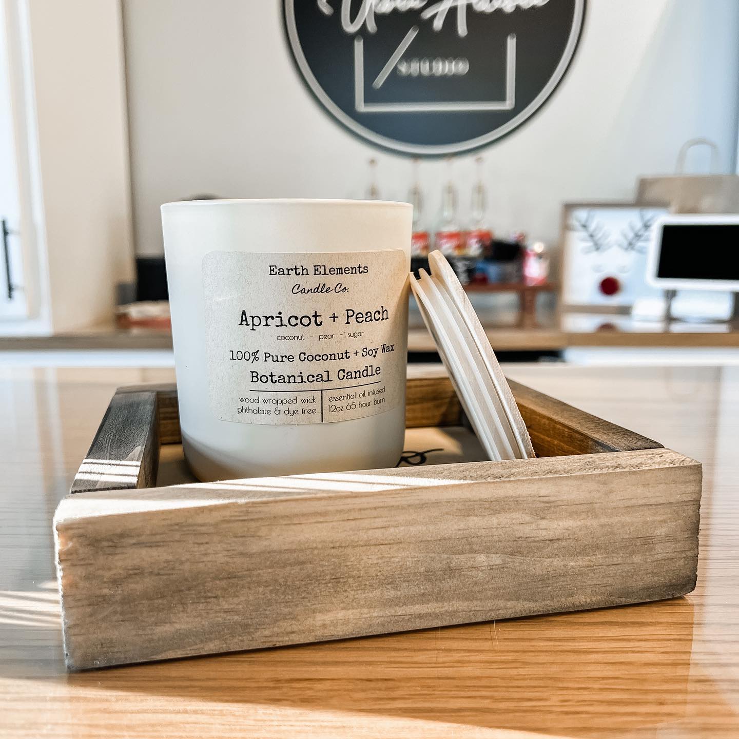 A white candle is sitting in a wooden box on a table.